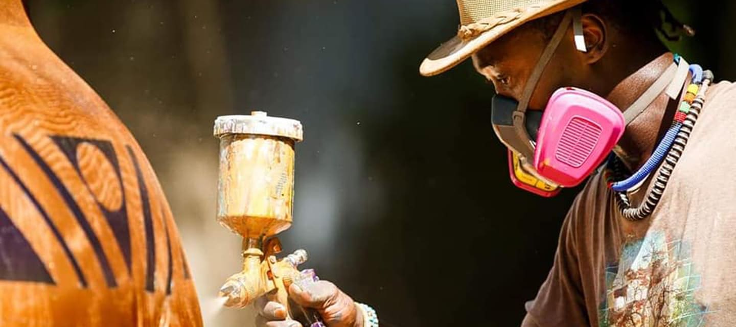 Colorful metallic statue of a jockey riding a horse outside a brick building.