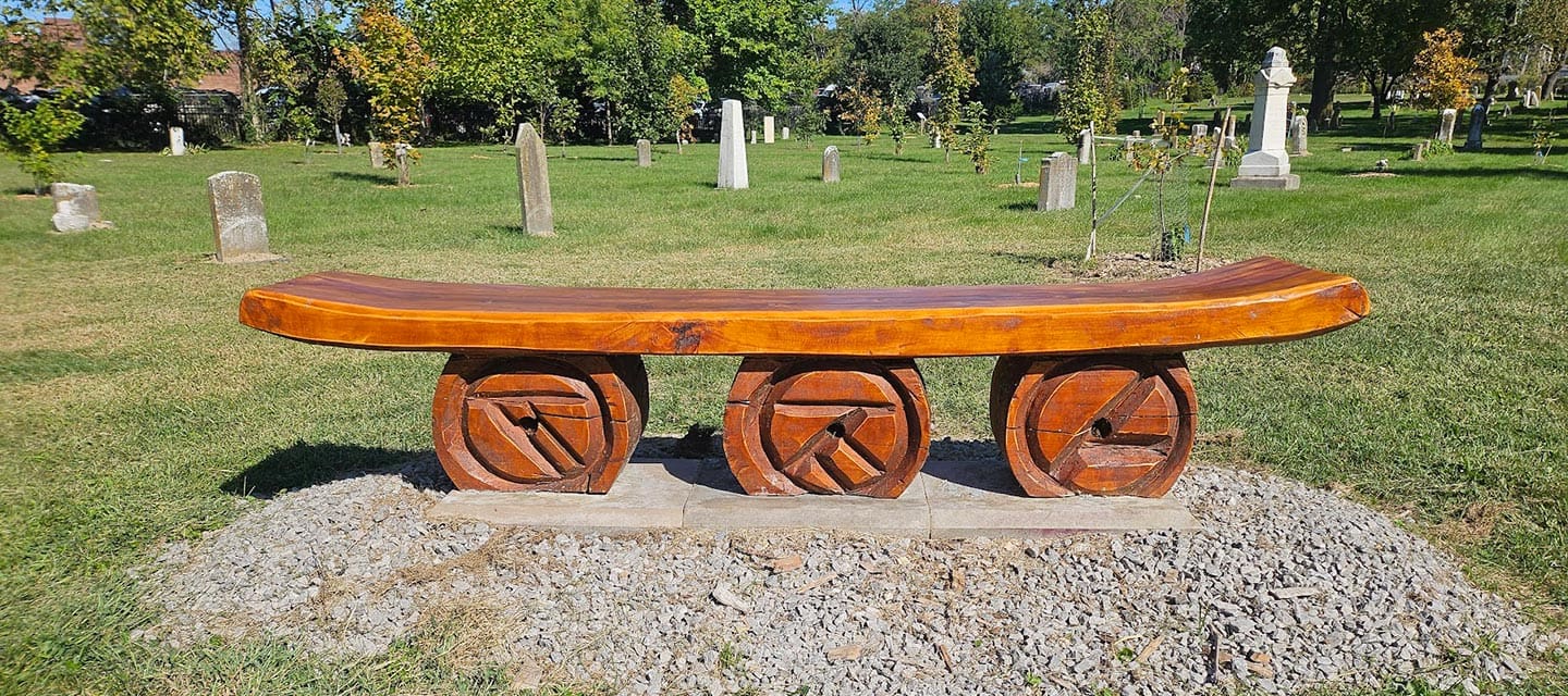 Colorful metallic statue of a jockey riding a horse outside a brick building.