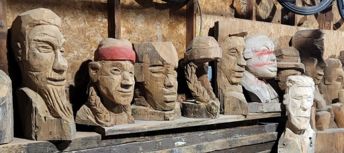 Colorful metallic statue of a jockey riding a horse outside a brick building.