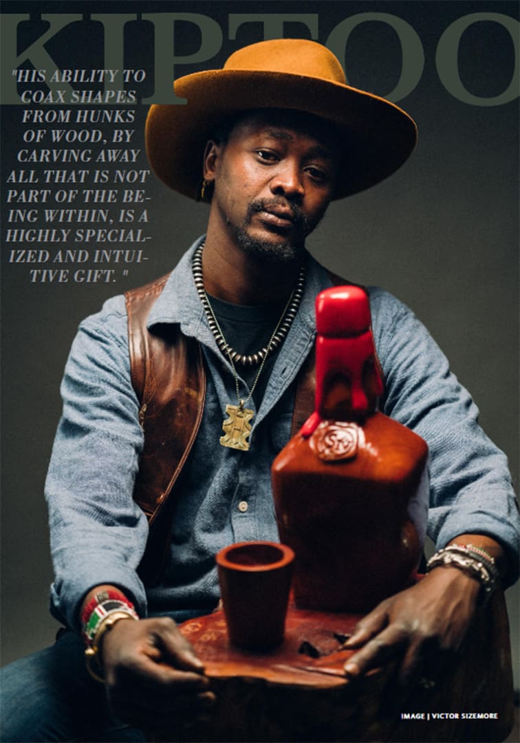 Portrait of a man wearing a brown fedora and denim shirt, seated with a carved wooden bottle and cup, a quote on the left, as a magazine cover image.