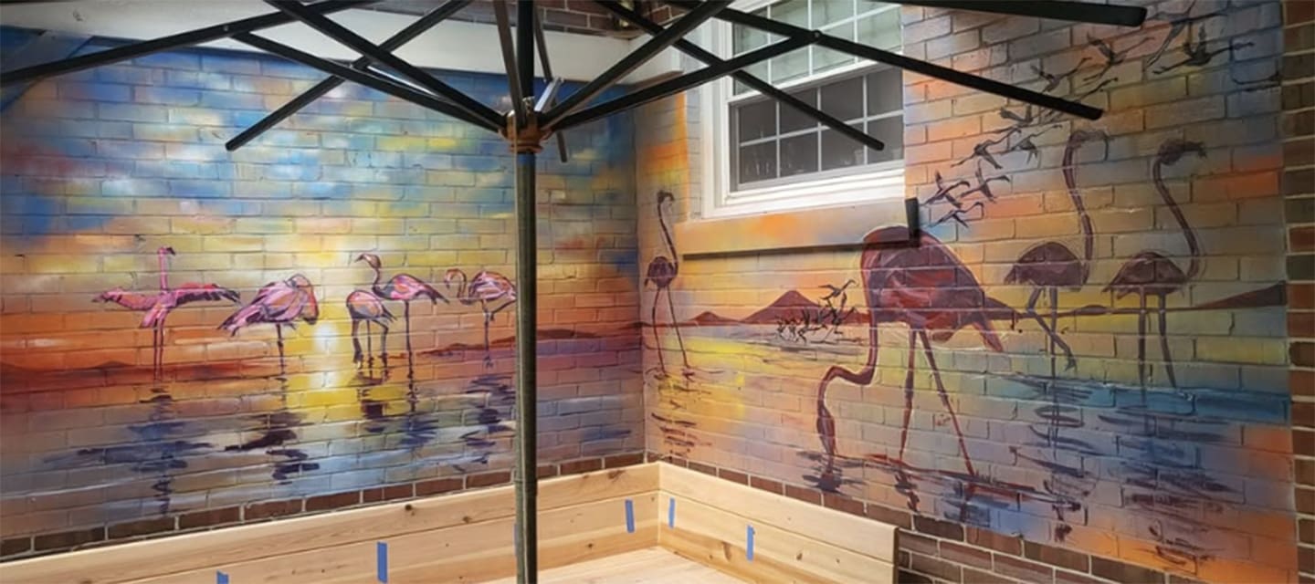 Colorful metallic statue of a jockey riding a horse outside a brick building.